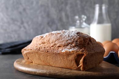 Photo of Tasty sponge cake with powdered sugar on grey table, closeup