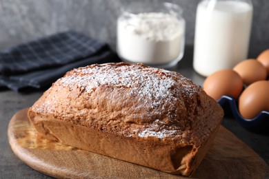 Photo of Tasty sponge cake with powdered sugar on grey table, closeup