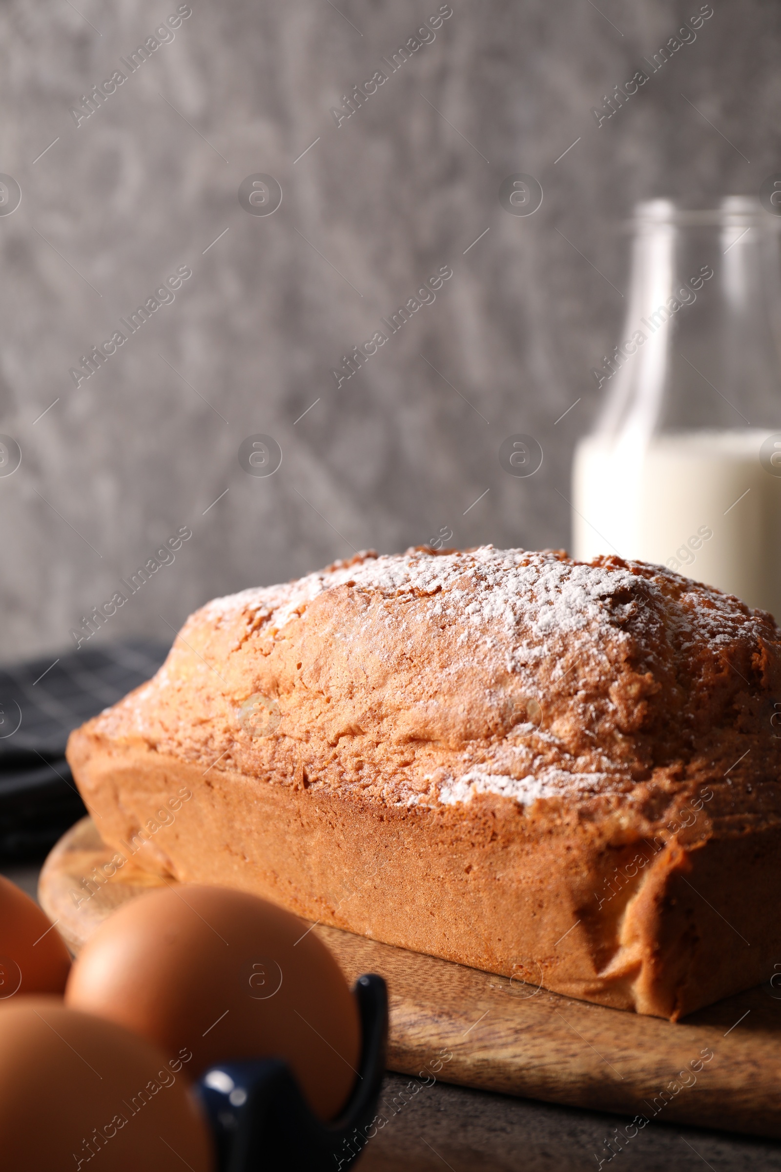 Photo of Tasty sponge cake with powdered sugar and ingredients on grey table