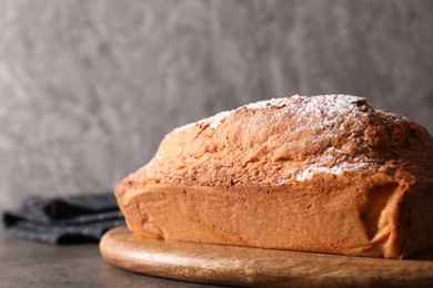 Photo of Tasty sponge cake with powdered sugar on grey table, closeup