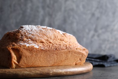 Photo of Tasty sponge cake with powdered sugar on grey table, closeup