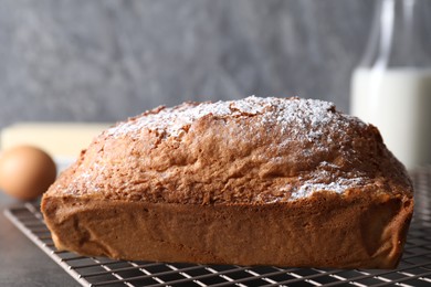 Photo of Tasty sponge cake with powdered sugar on grey table, closeup