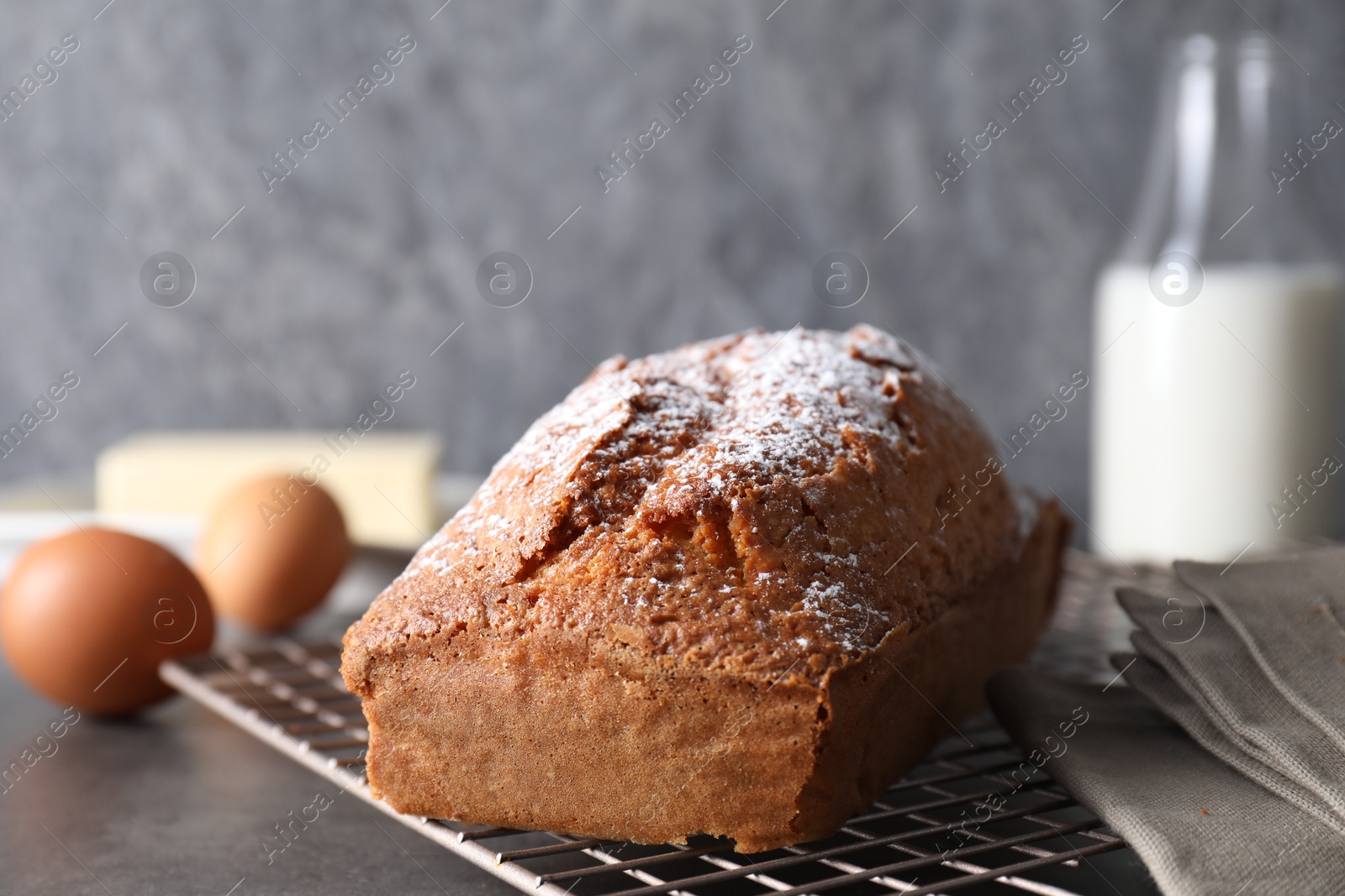 Photo of Tasty sponge cake with powdered sugar on grey table, closeup