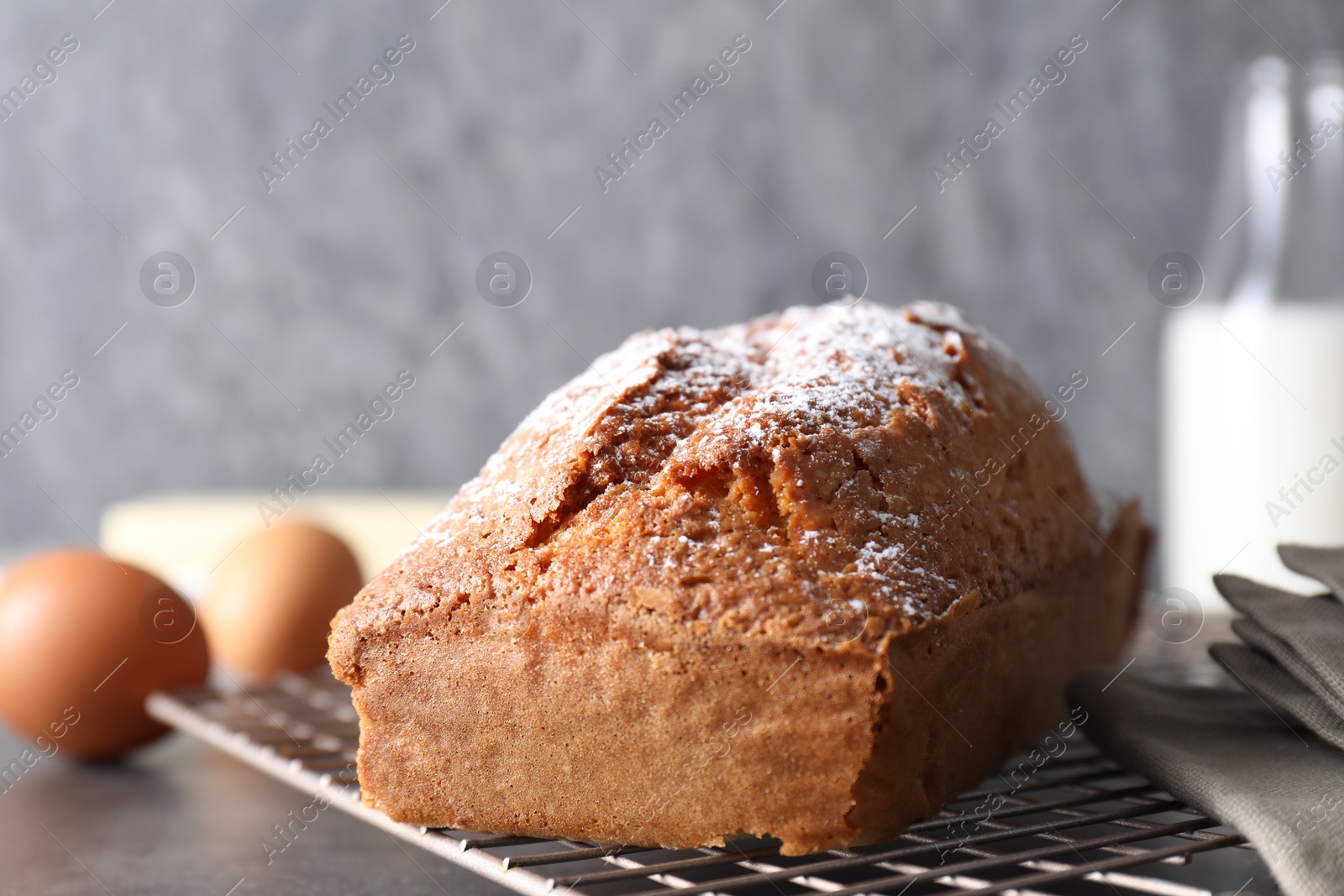 Photo of Tasty sponge cake with powdered sugar on grey table, closeup