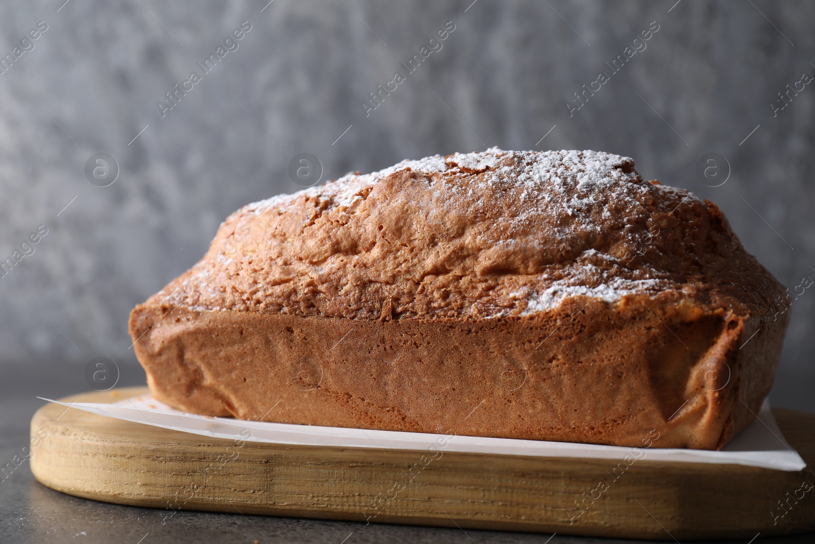 Photo of Tasty sponge cake with powdered sugar on grey table, closeup