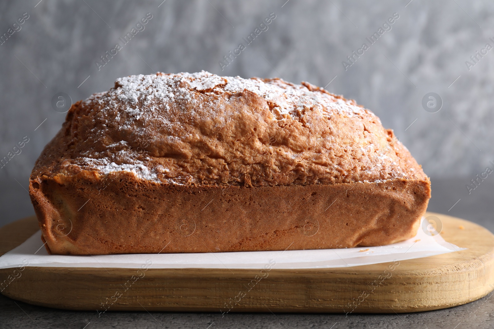 Photo of Tasty sponge cake with powdered sugar on grey table, closeup