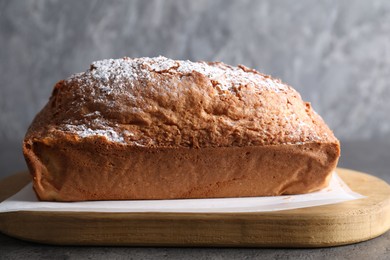 Photo of Tasty sponge cake with powdered sugar on grey table, closeup