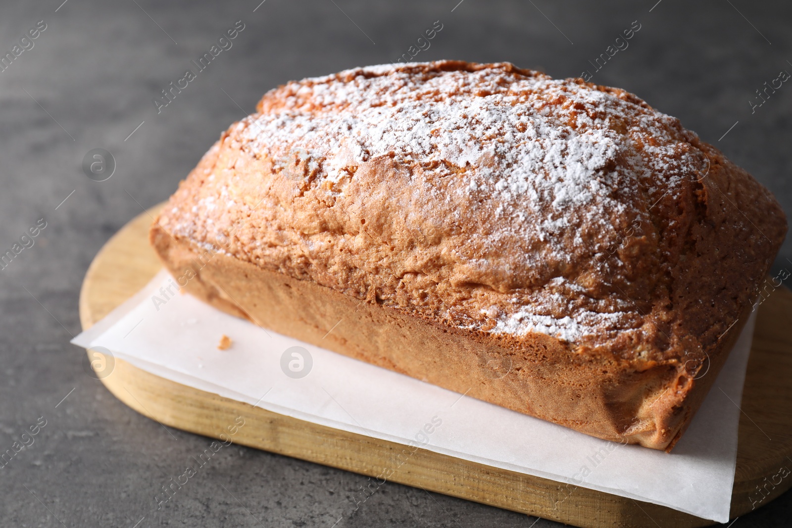 Photo of Tasty sponge cake with powdered sugar on grey table, closeup