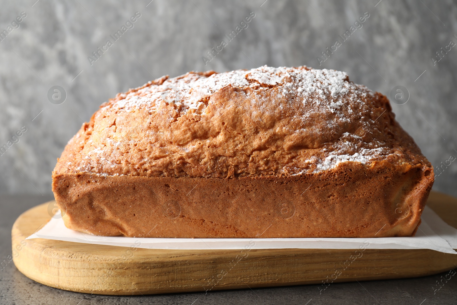 Photo of Tasty sponge cake with powdered sugar on grey table, closeup