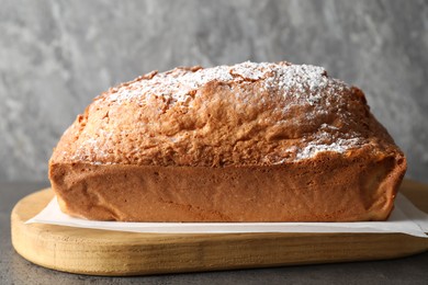 Photo of Tasty sponge cake with powdered sugar on grey table, closeup