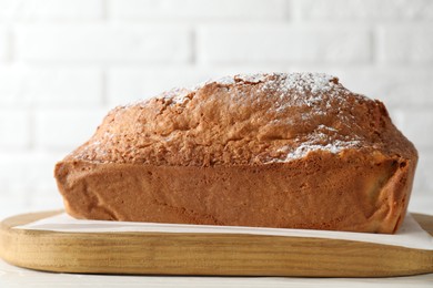 Photo of Tasty sponge cake with powdered sugar on white table, closeup