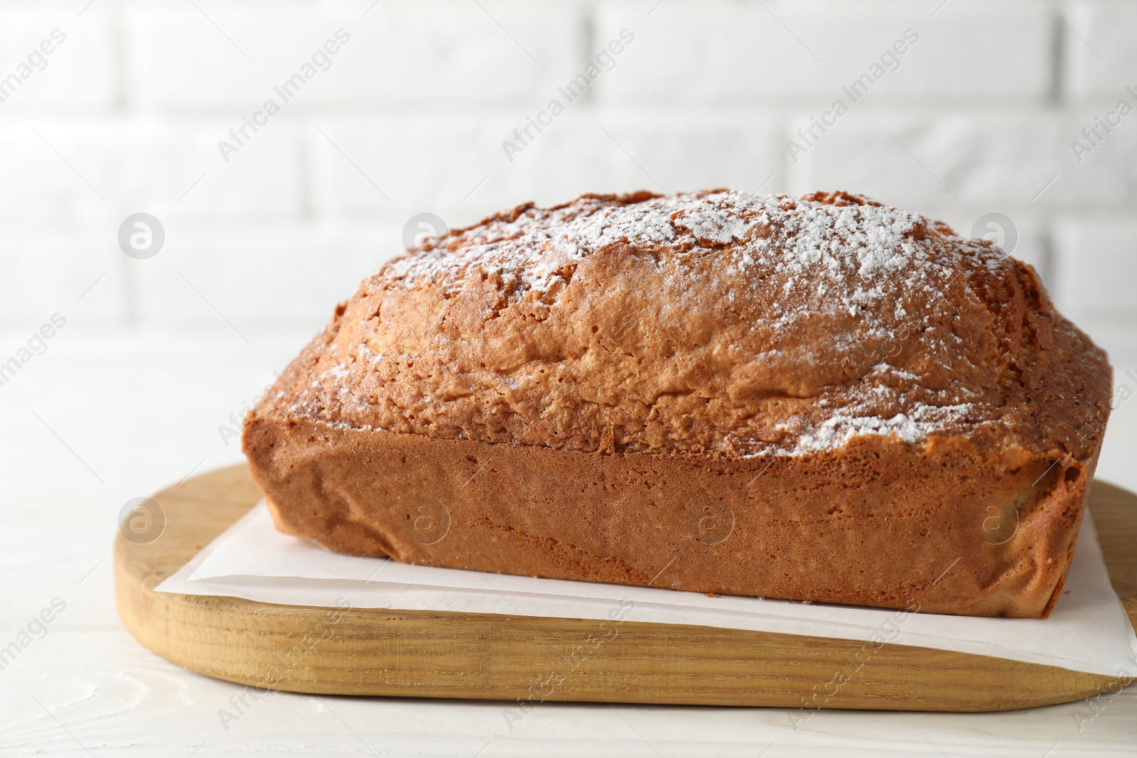 Photo of Tasty sponge cake with powdered sugar on white table, closeup