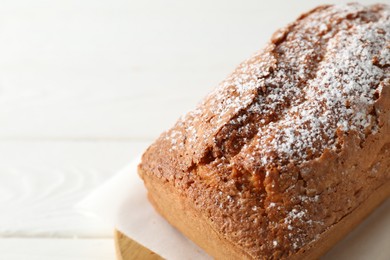 Photo of Tasty sponge cake with powdered sugar on white table, closeup. Space for text