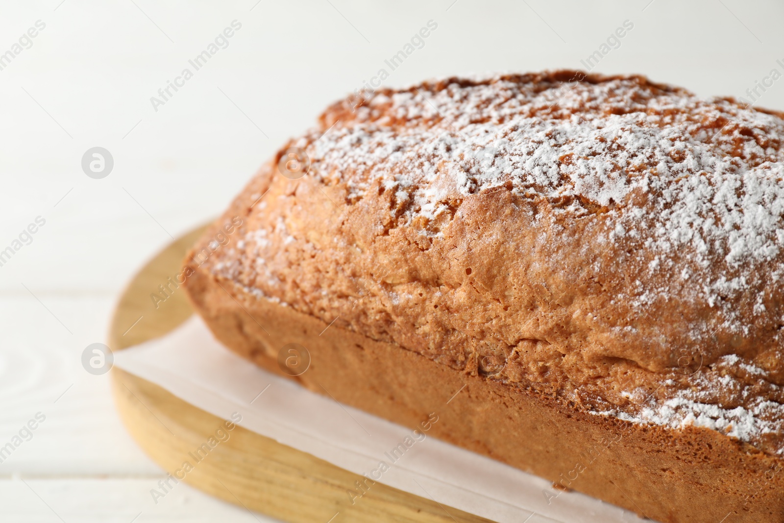 Photo of Tasty sponge cake with powdered sugar on white table, closeup