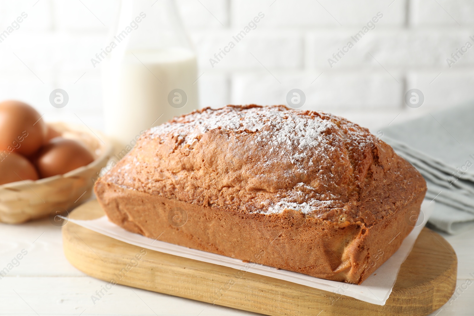 Photo of Tasty sponge cake with powdered sugar on white table, closeup