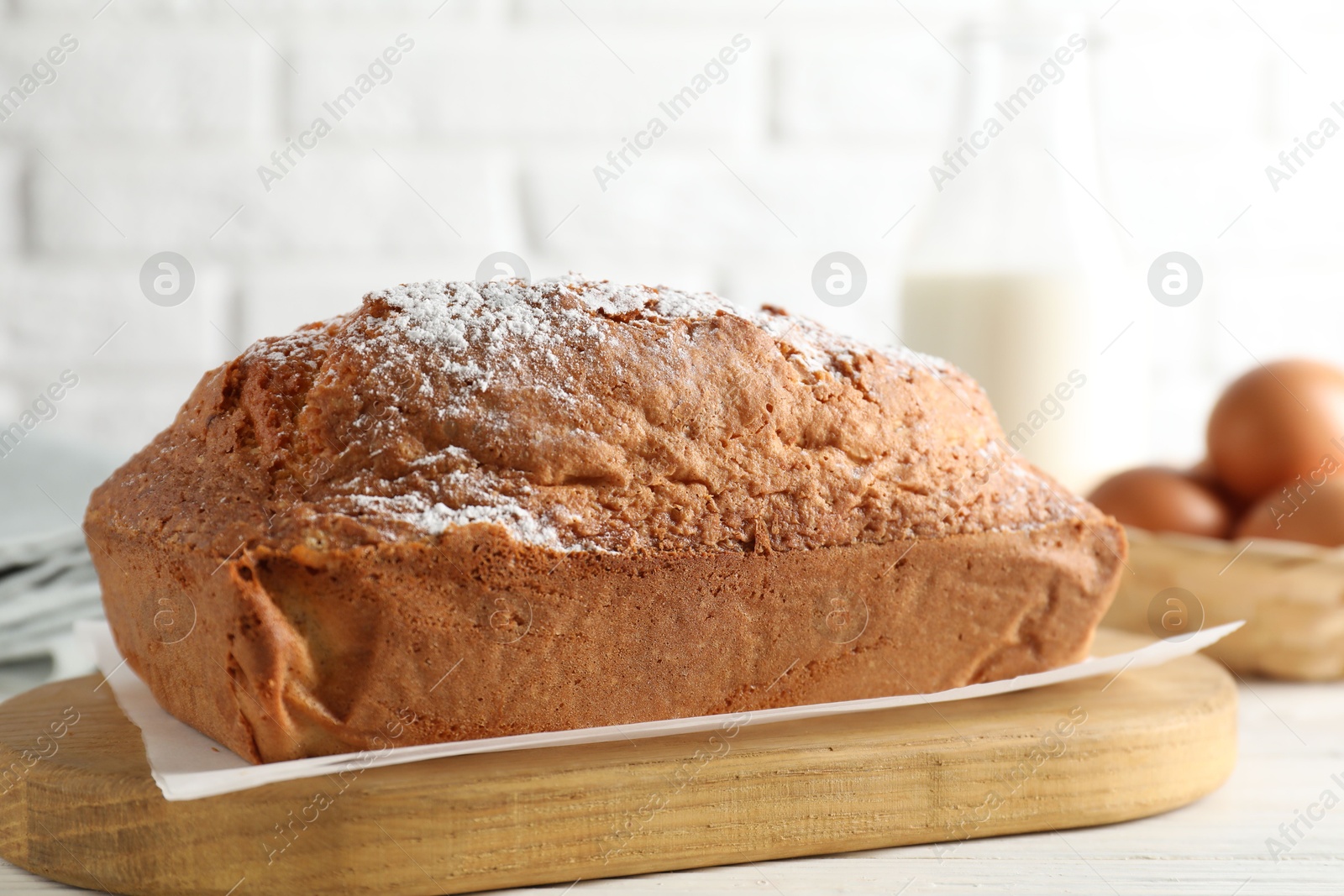 Photo of Tasty sponge cake with powdered sugar on white table, closeup