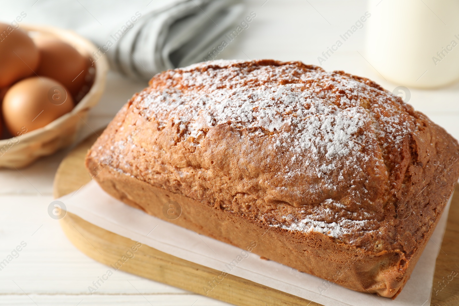 Photo of Tasty sponge cake with powdered sugar on white table, closeup