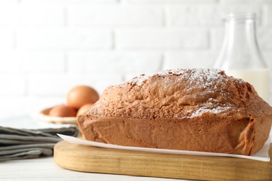 Photo of Tasty sponge cake with powdered sugar on white table, closeup