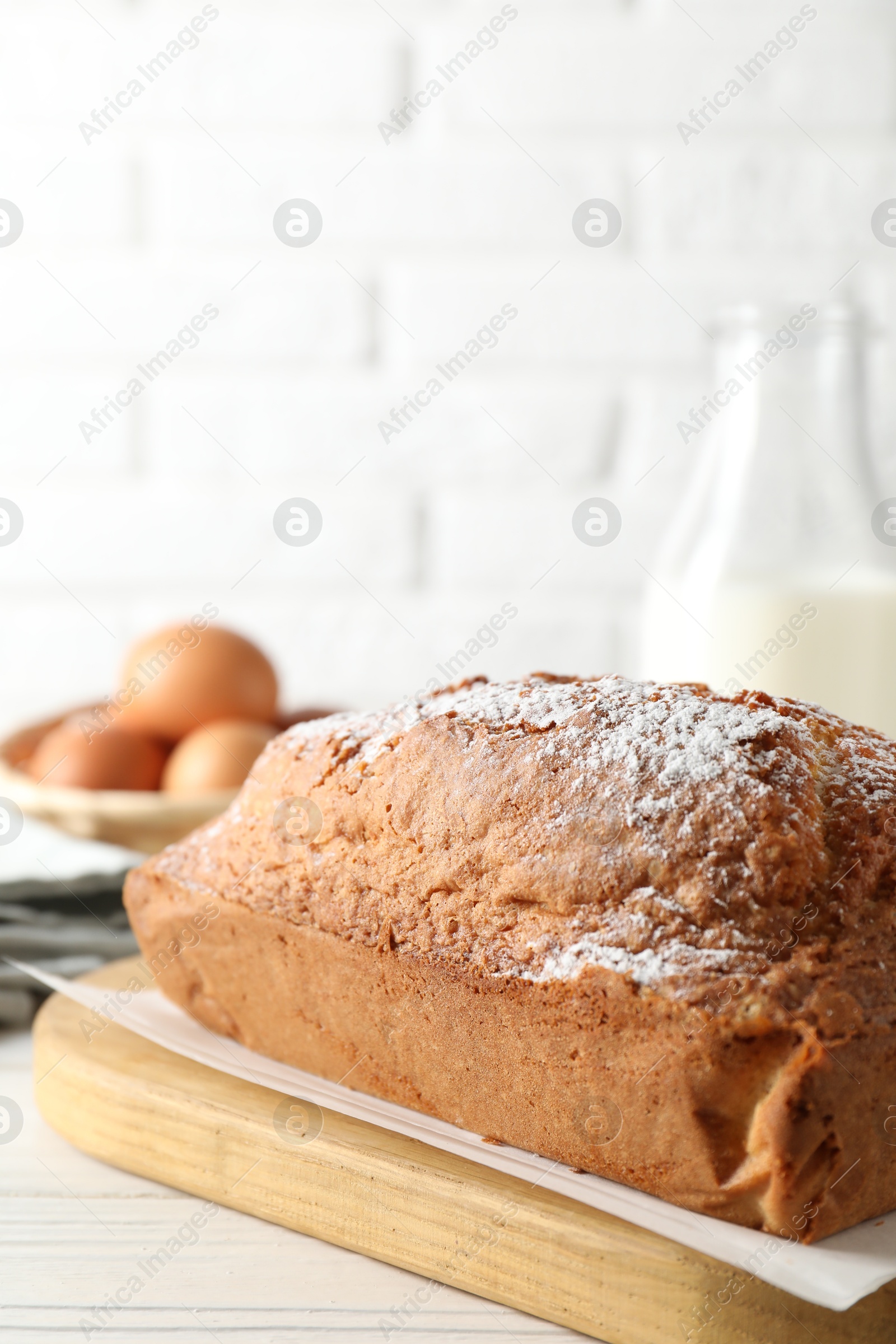 Photo of Tasty sponge cake with powdered sugar on white table, closeup