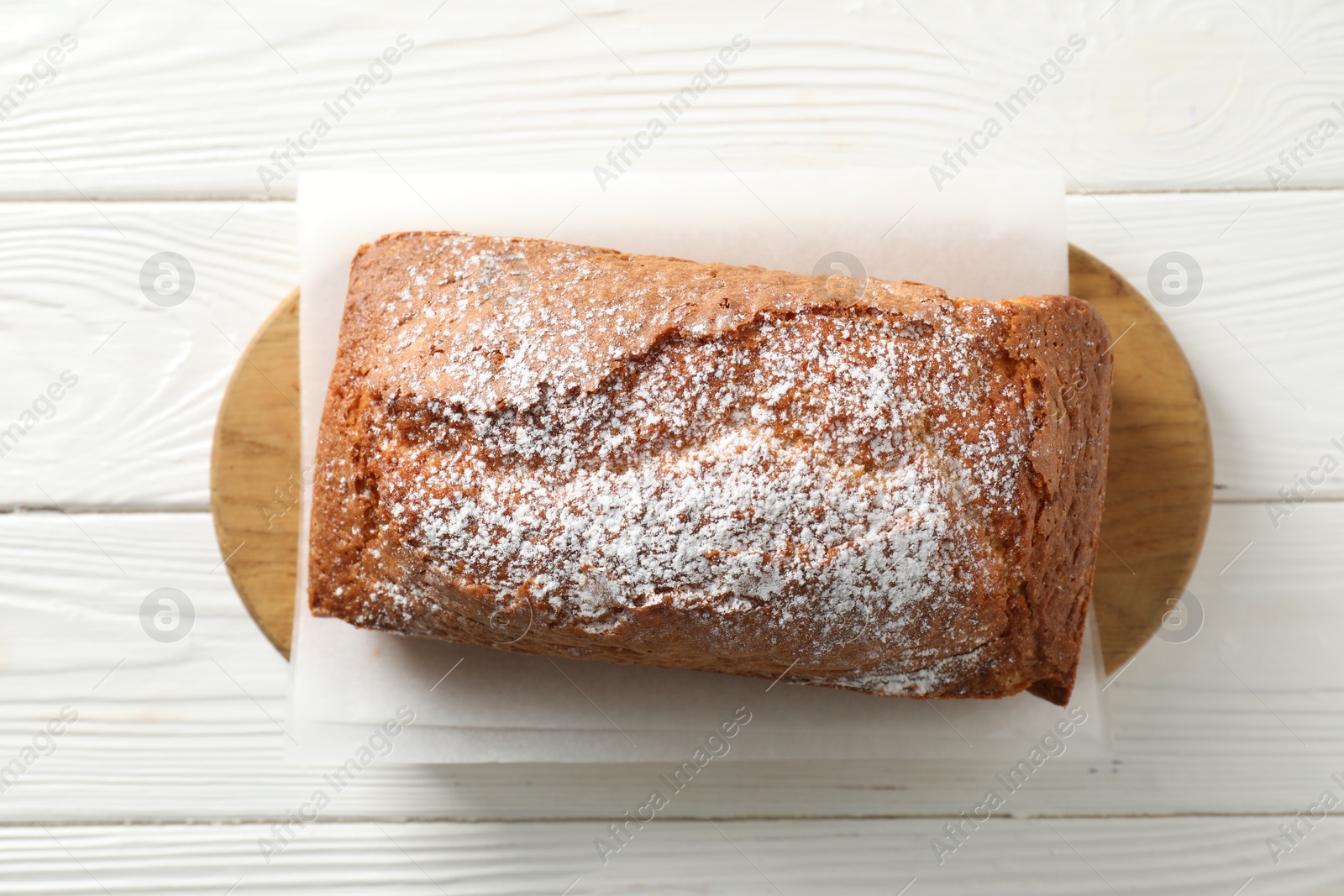 Photo of Tasty sponge cake with powdered sugar on white wooden table, top view