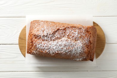 Photo of Tasty sponge cake with powdered sugar on white wooden table, top view