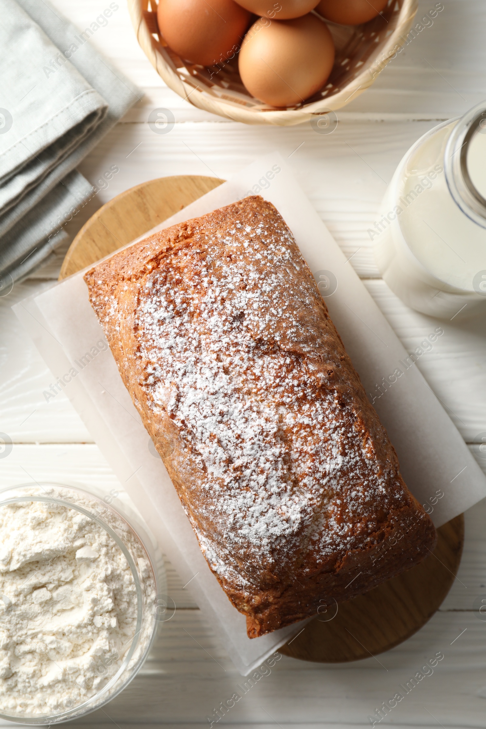 Photo of Tasty sponge cake with ingredients on white wooden table, flat lay