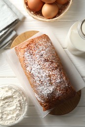 Photo of Tasty sponge cake with ingredients on white wooden table, flat lay