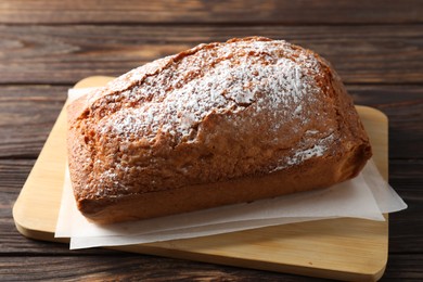 Photo of Tasty sponge cake with powdered sugar on wooden table, closeup