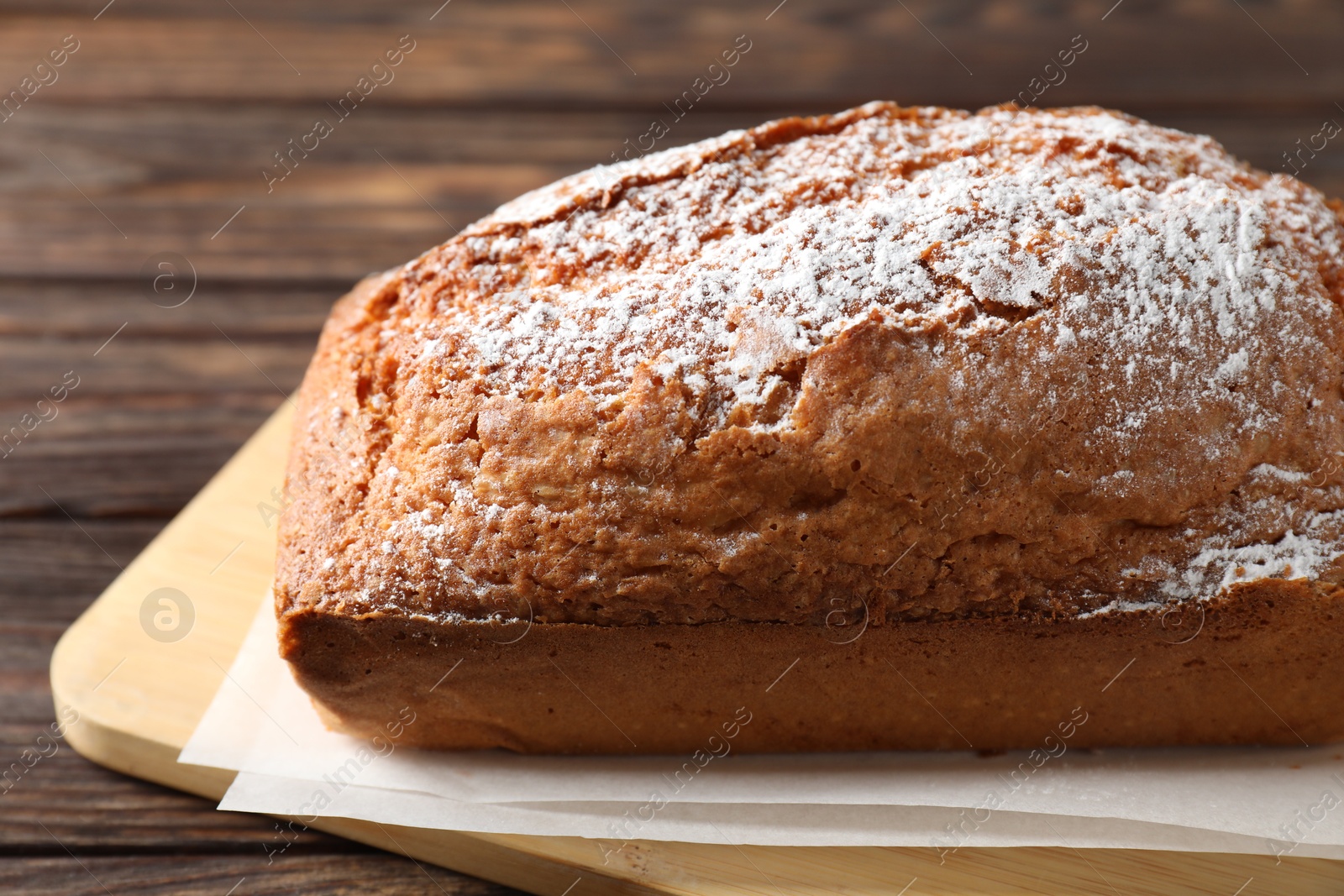 Photo of Tasty sponge cake with powdered sugar on wooden table, closeup