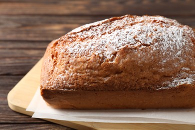 Photo of Tasty sponge cake with powdered sugar on wooden table, closeup