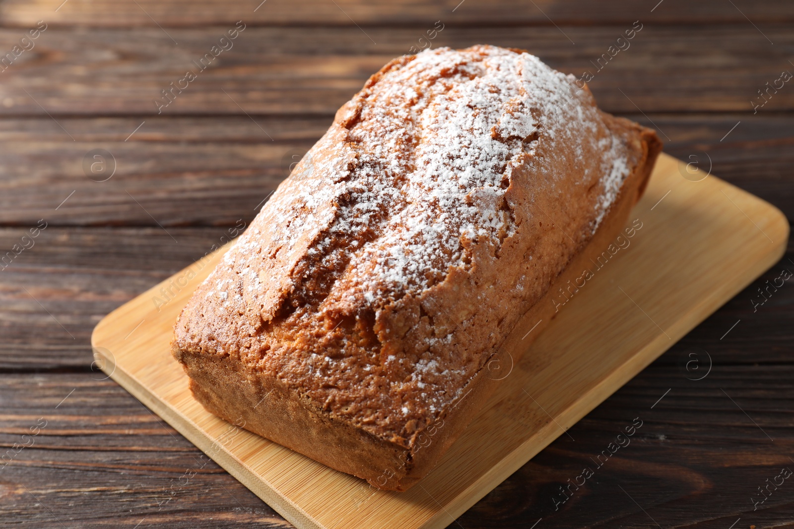 Photo of Tasty sponge cake with powdered sugar on wooden table, closeup