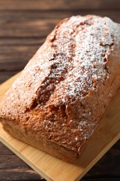 Photo of Tasty sponge cake with powdered sugar on wooden table, closeup