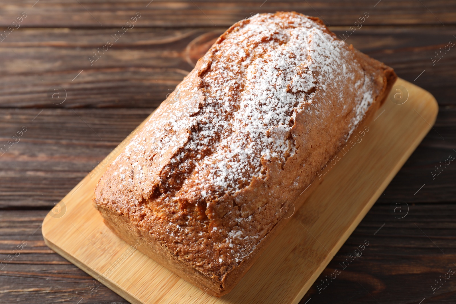 Photo of Tasty sponge cake with powdered sugar on wooden table, closeup