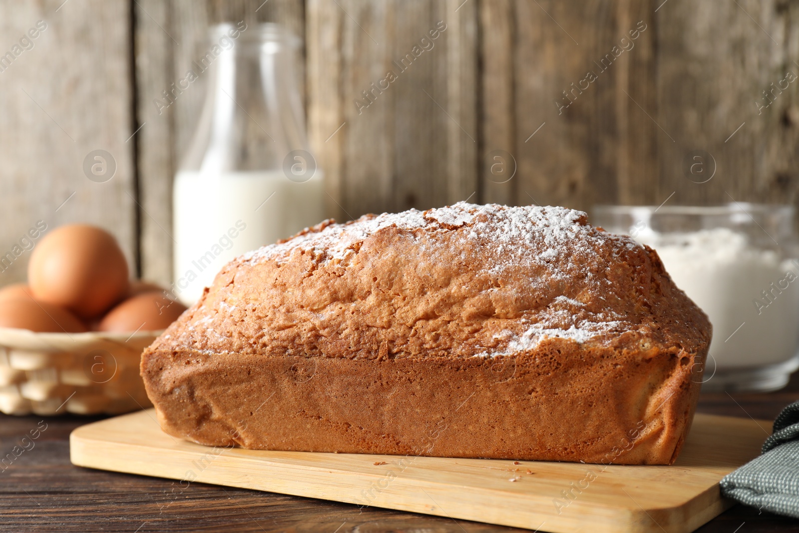 Photo of Tasty sponge cake with powdered sugar on wooden table, closeup