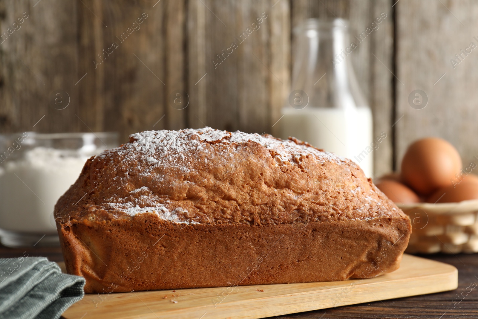 Photo of Tasty sponge cake with powdered sugar on wooden table, closeup