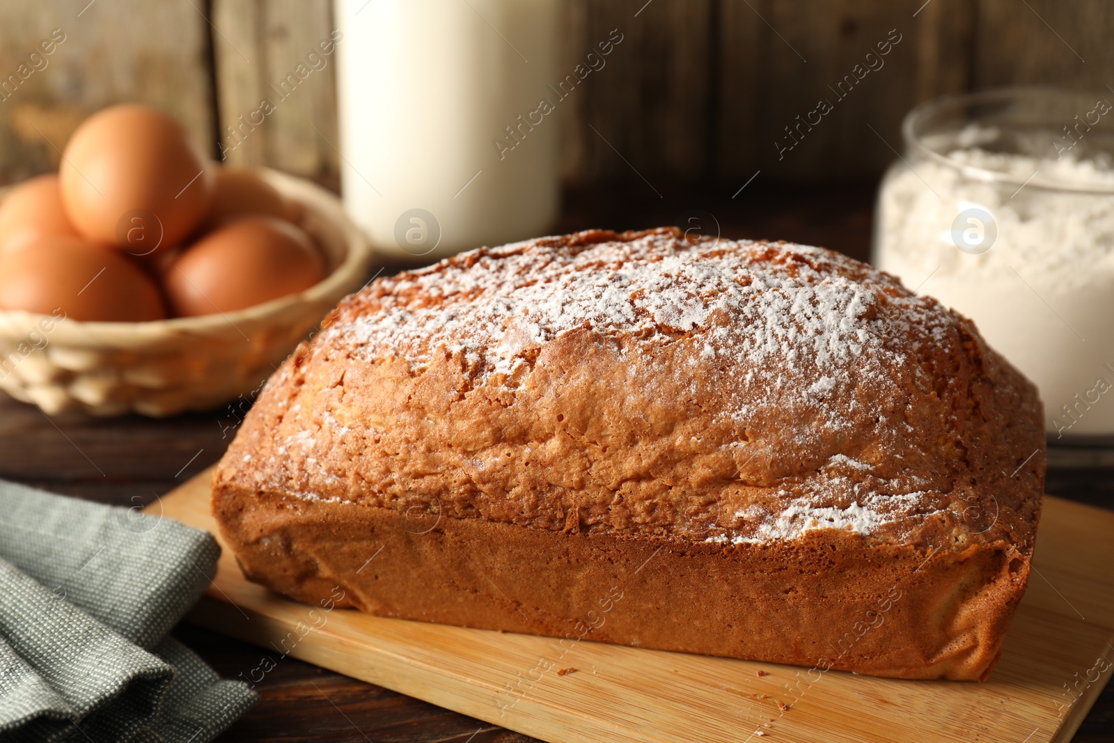 Photo of Tasty sponge cake with powdered sugar on wooden table, closeup