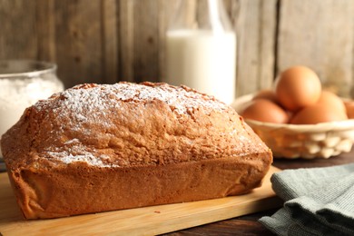 Photo of Tasty sponge cake with powdered sugar on wooden table, closeup