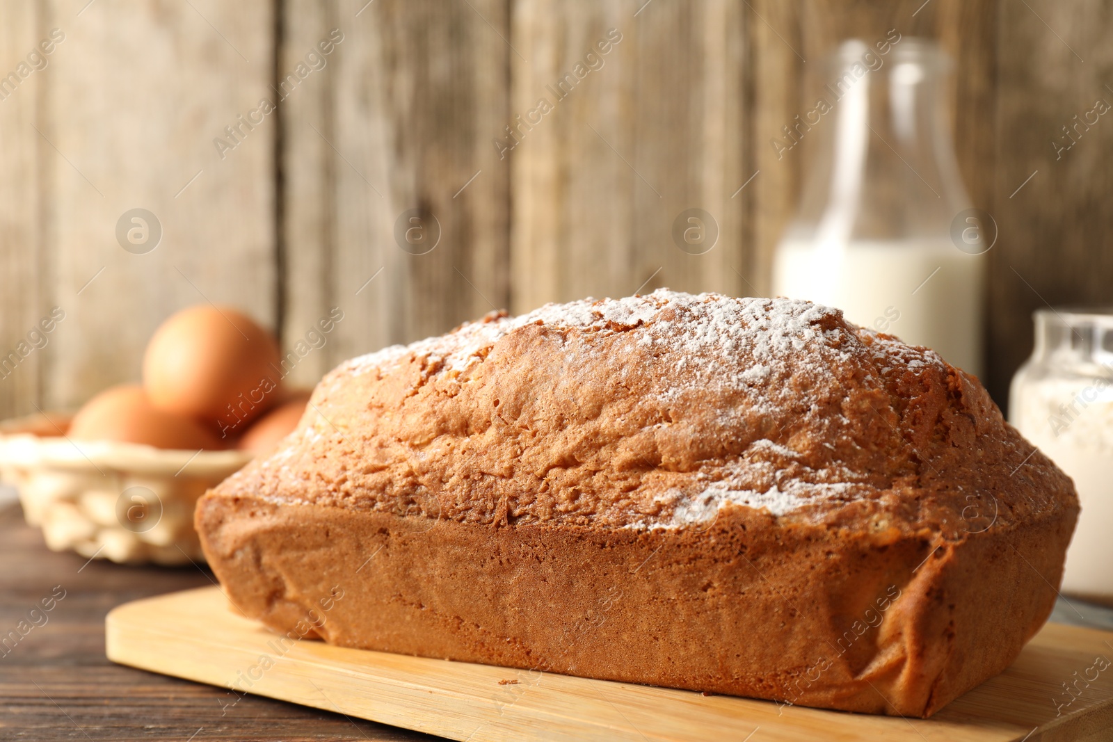 Photo of Tasty sponge cake with powdered sugar on wooden table, closeup