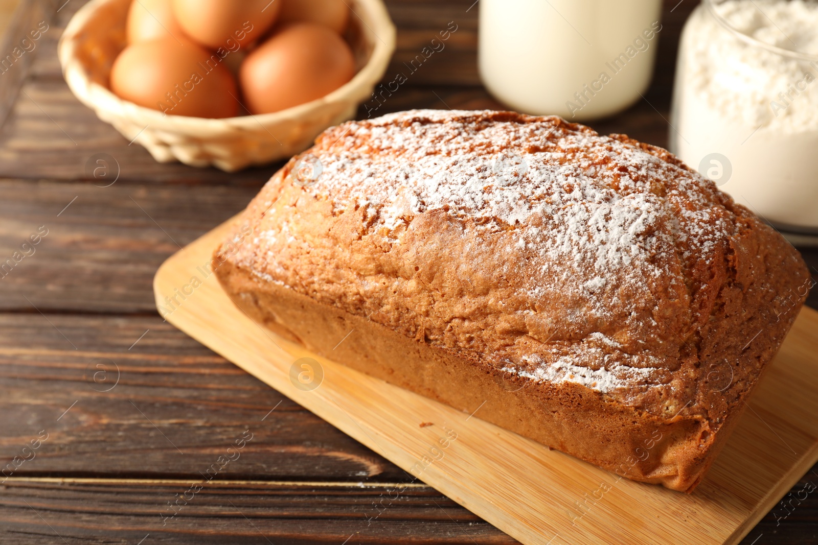 Photo of Tasty sponge cake with powdered sugar on wooden table, closeup