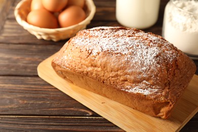 Photo of Tasty sponge cake with powdered sugar on wooden table, closeup