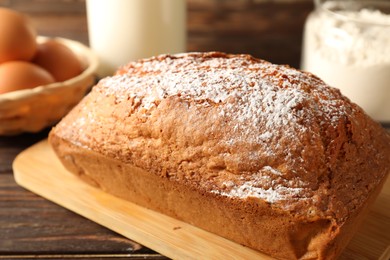 Photo of Tasty sponge cake with powdered sugar on wooden table, closeup