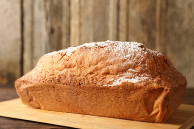 Photo of Tasty sponge cake with powdered sugar on wooden table, closeup