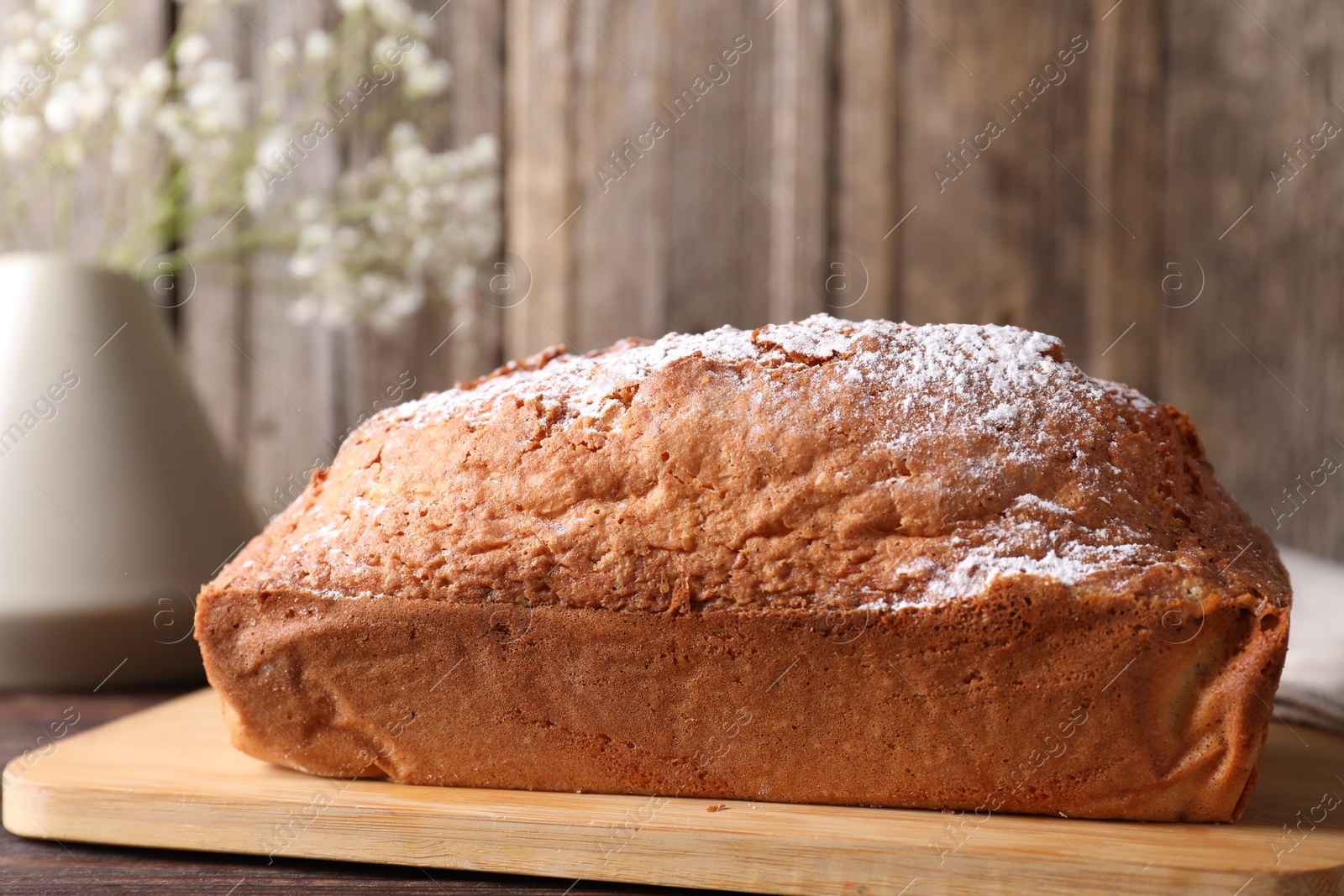 Photo of Tasty sponge cake with powdered sugar on wooden table, closeup