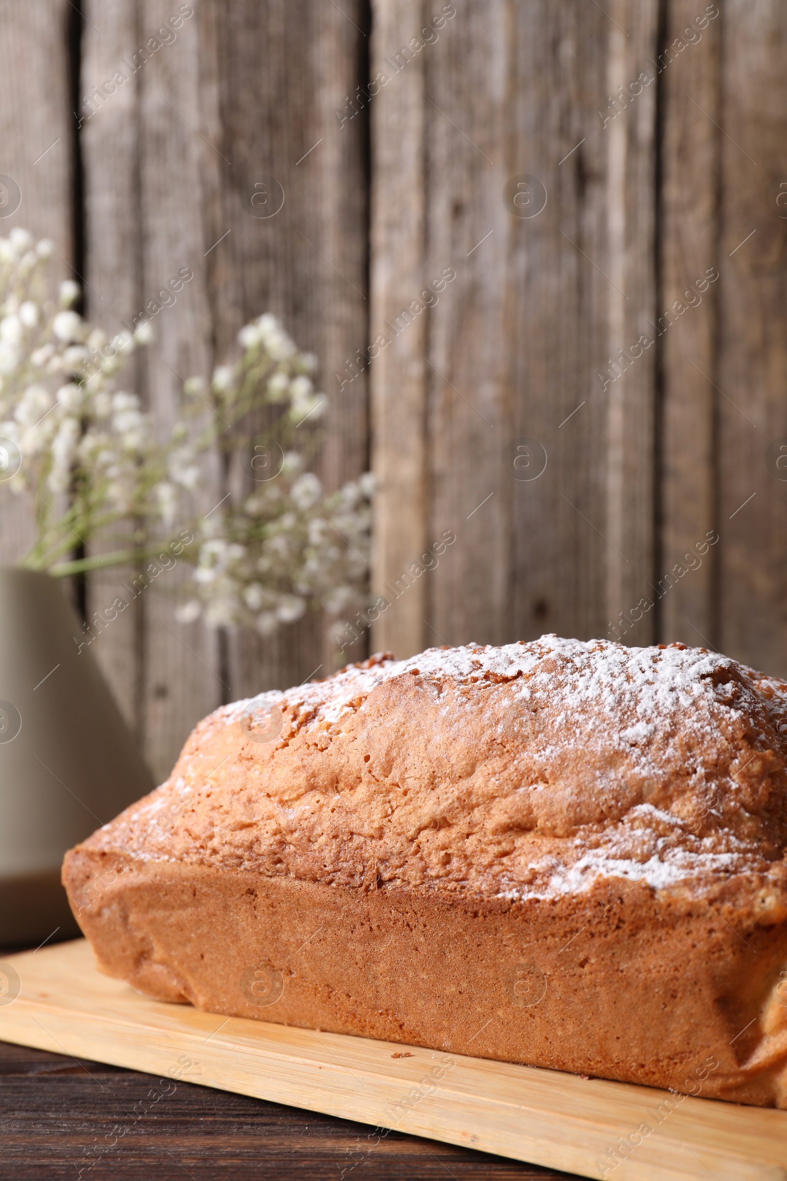 Photo of Tasty sponge cake with powdered sugar on wooden table, closeup