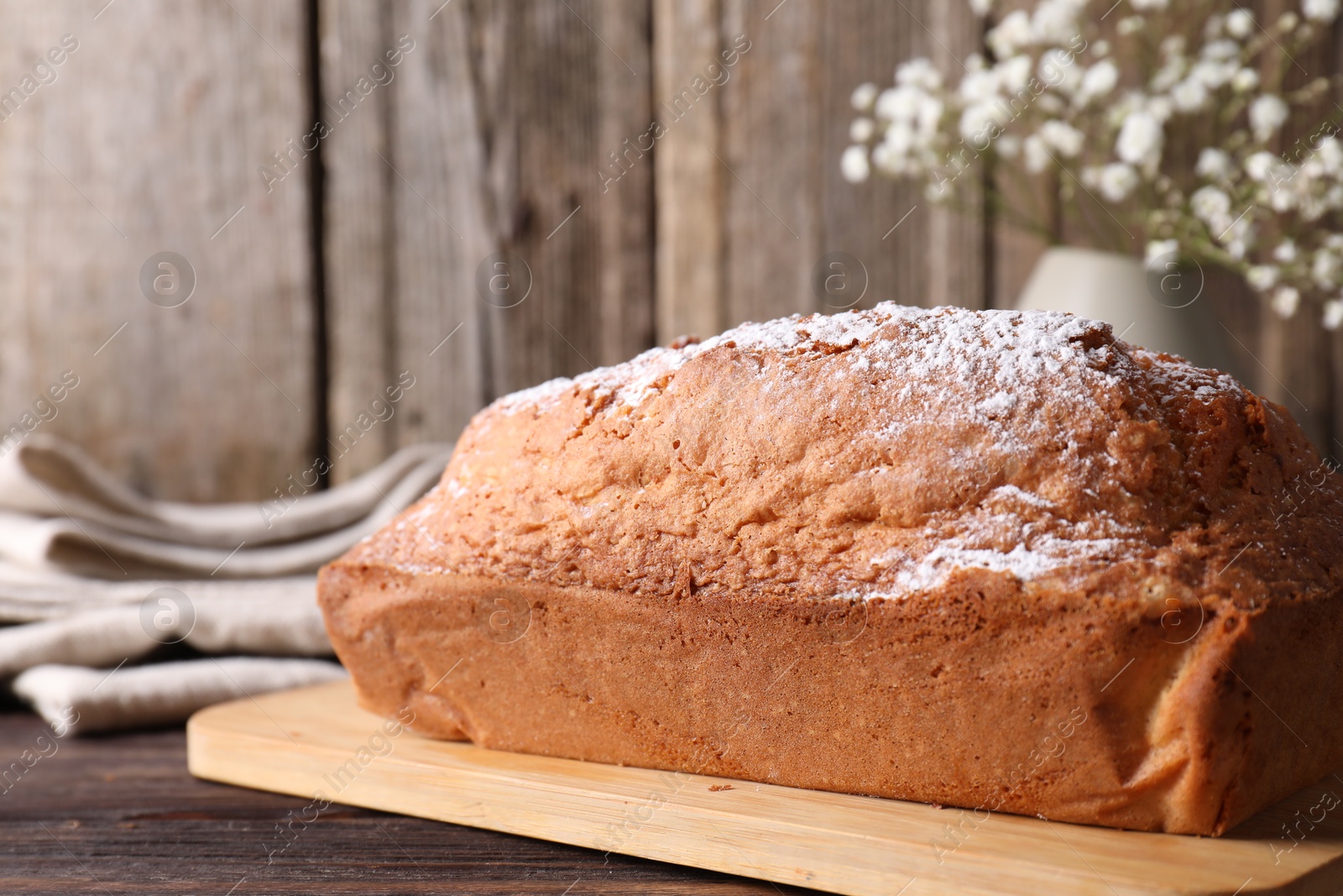 Photo of Tasty sponge cake with powdered sugar on wooden table, closeup