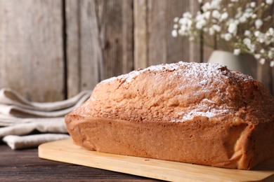 Photo of Tasty sponge cake with powdered sugar on wooden table, closeup