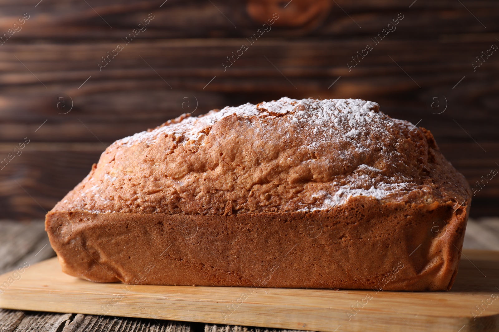 Photo of Tasty sponge cake with powdered sugar on wooden table, closeup