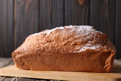 Photo of Tasty sponge cake with powdered sugar on wooden table, closeup