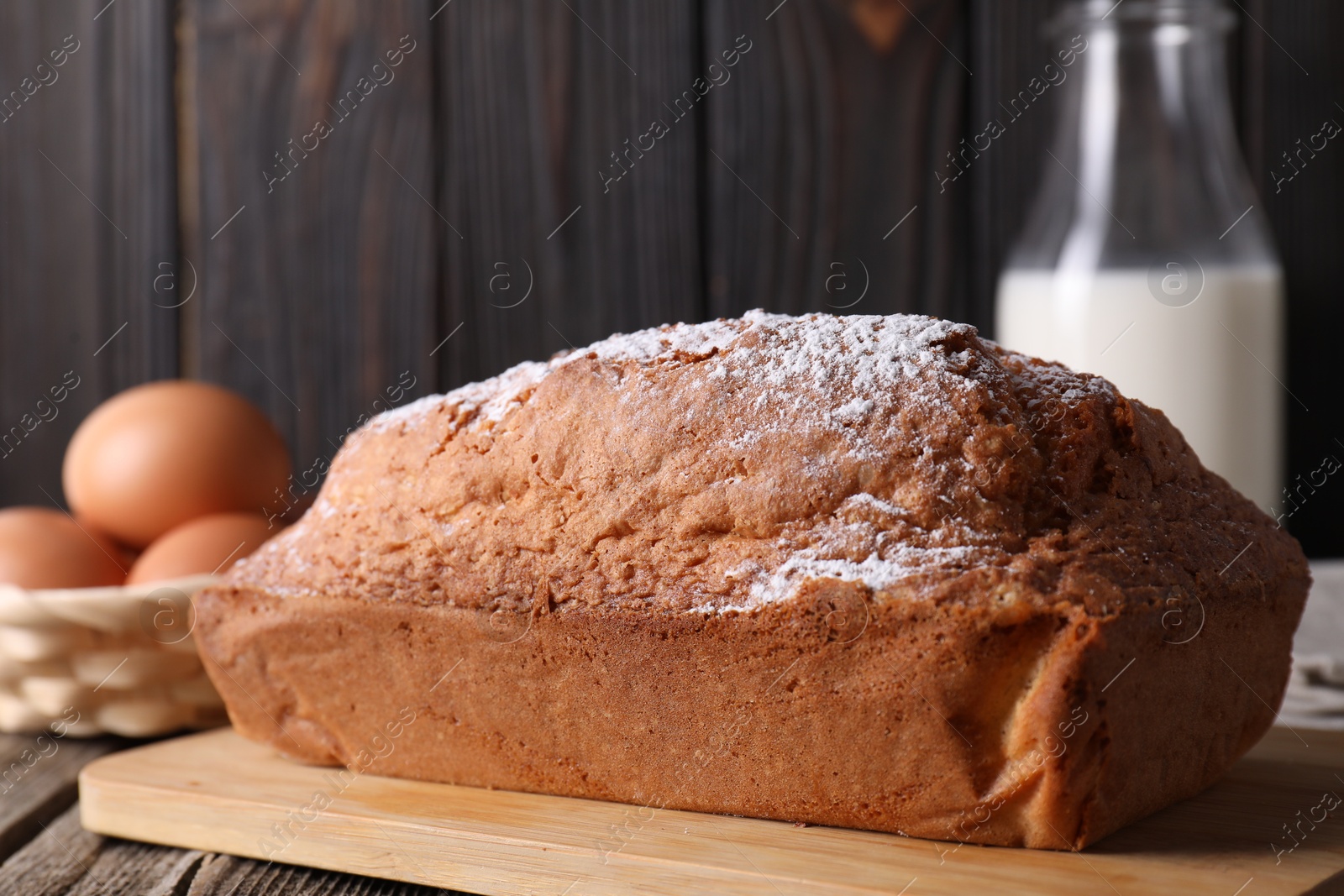 Photo of Tasty sponge cake with powdered sugar on wooden table, closeup