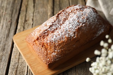 Photo of Tasty sponge cake with powdered sugar on wooden table, closeup